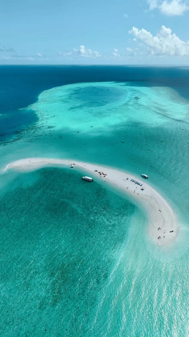 Playa de arena blanca y aguas turquesas en Isla Contadora, Panamá, con yates privados anclados cerca de la orilla.